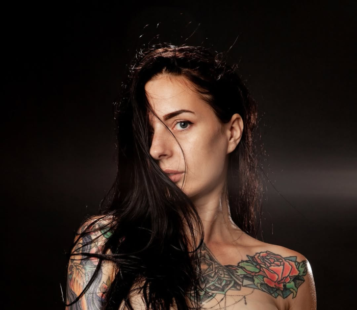 a woman with tattoos and a black background